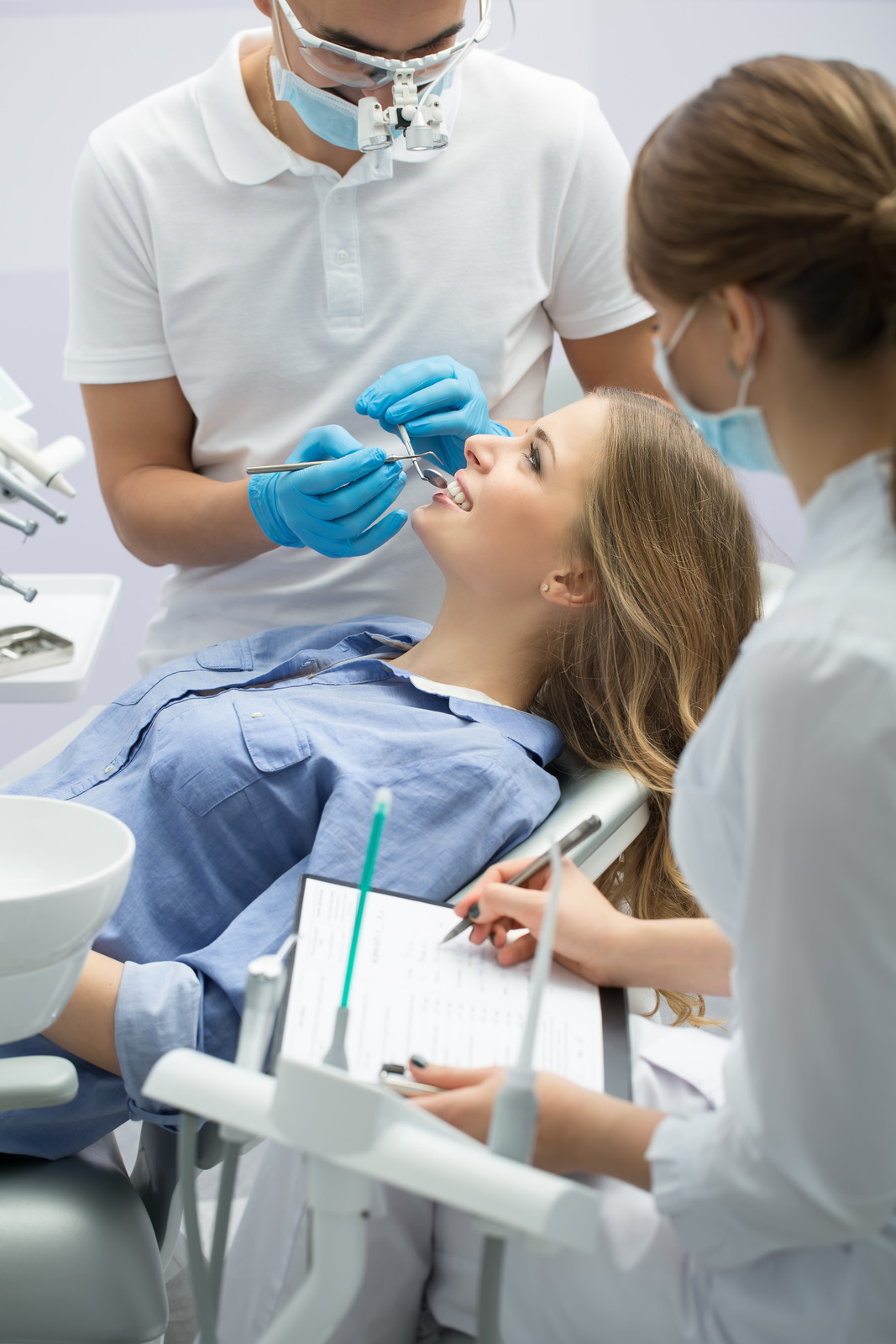 A dentist from Dental Logic is treating a female blonde patient in the dental treatment room.