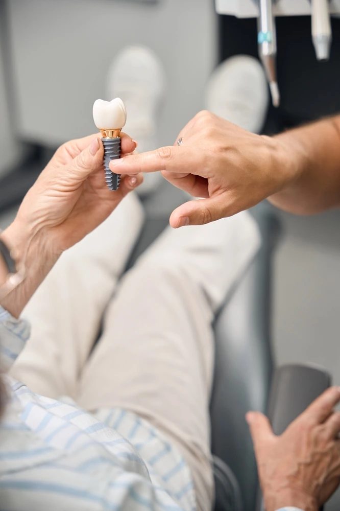 Dental Logic female patient holds model of dental implant in hands